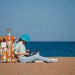 a person sitting on the beach with a suitcase