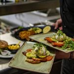 a man holding two trays of food