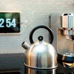 a tea kettle sitting on top of a counter next to a cup