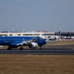 Blue airplane taxiing on airport runway